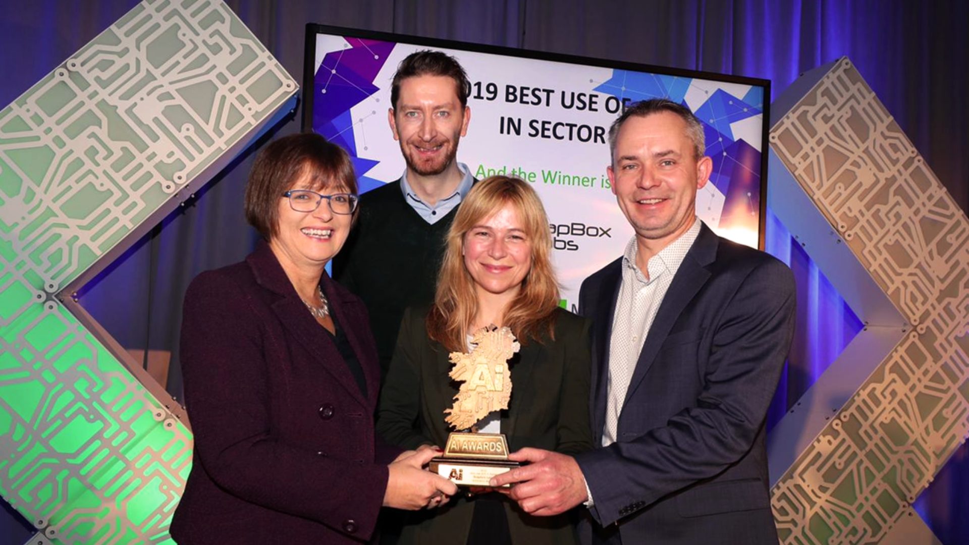 An image of four people holding a trophy, two women and two men.