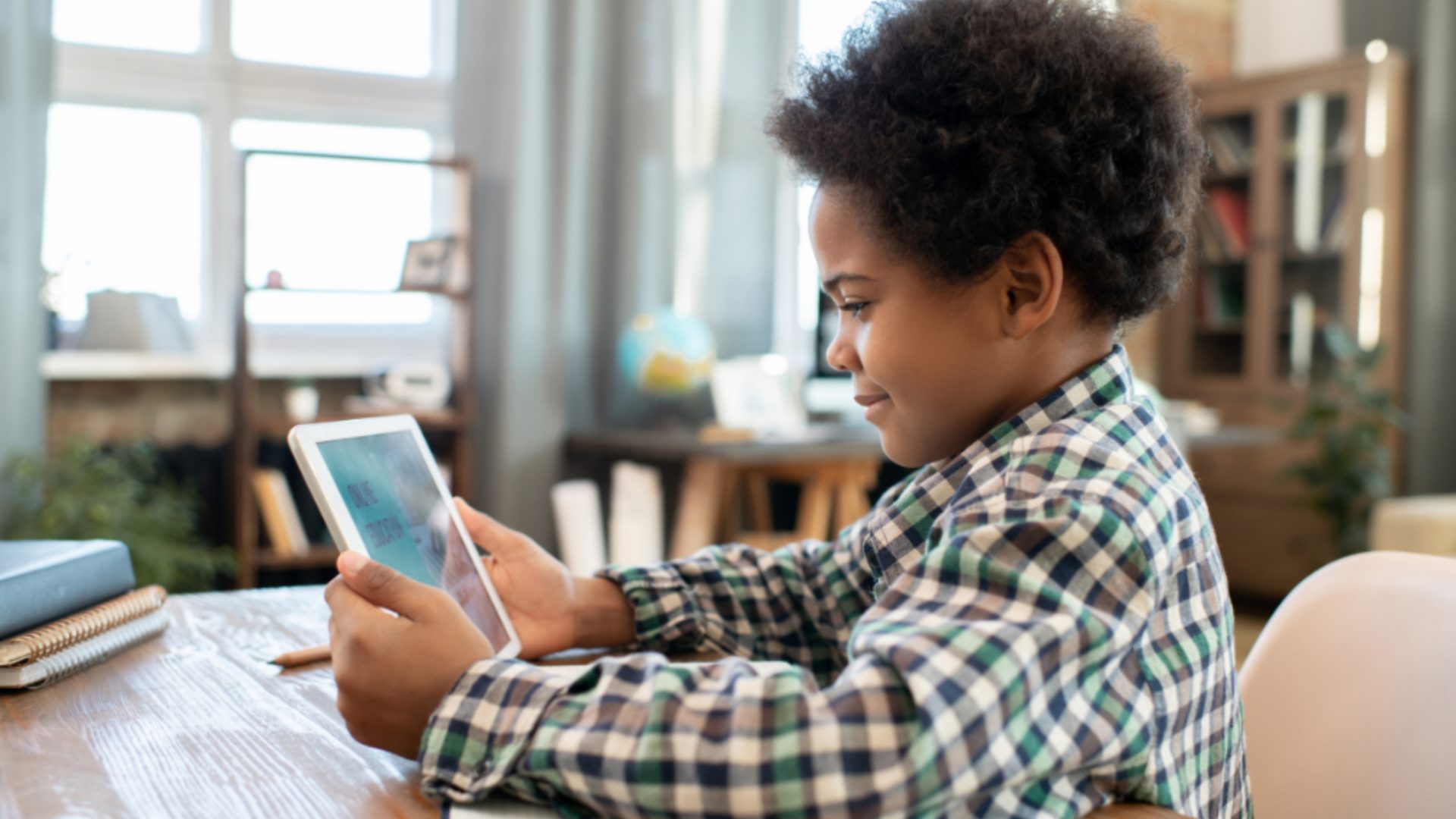 A photo of a young boy sitting at a desk, completing a voice-enabled literacy assessment.