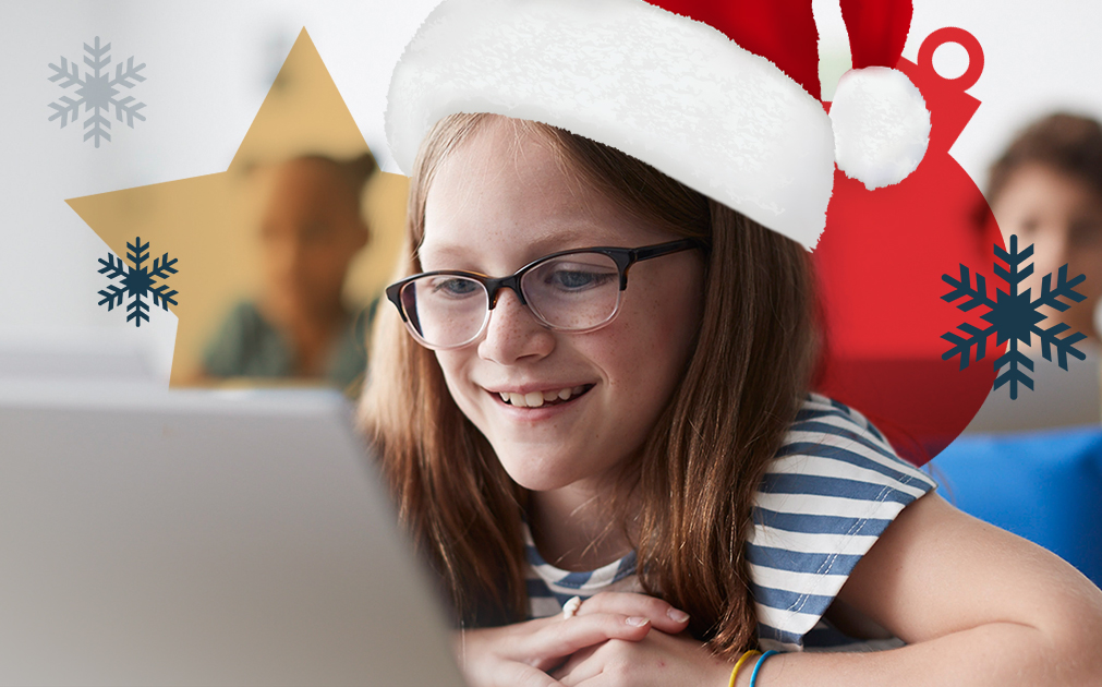 A photo of an eight-year-old girl sitting in a classroom, reading off of an iPad. The girl is wearing a Santa hat.