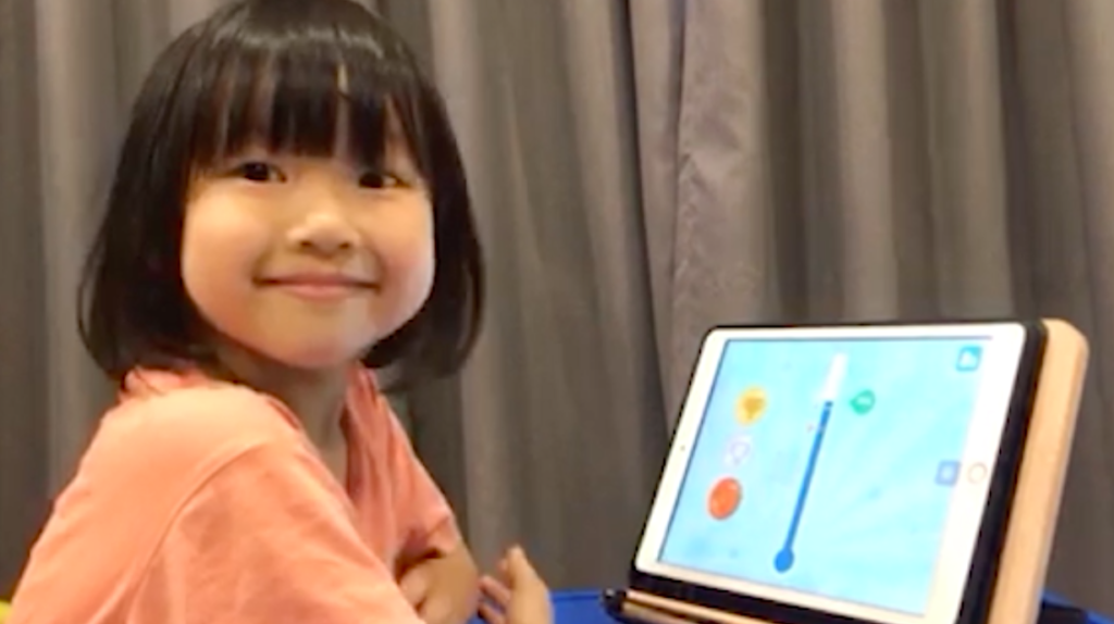 A young girl smiling after completing a voice-enabled language learning lesson on an iPad.