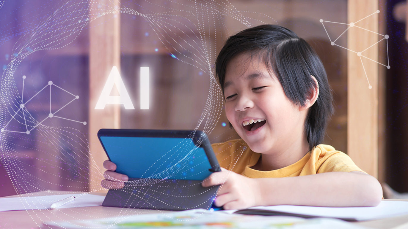 A boy sitting at a desk, talking into an iPad.