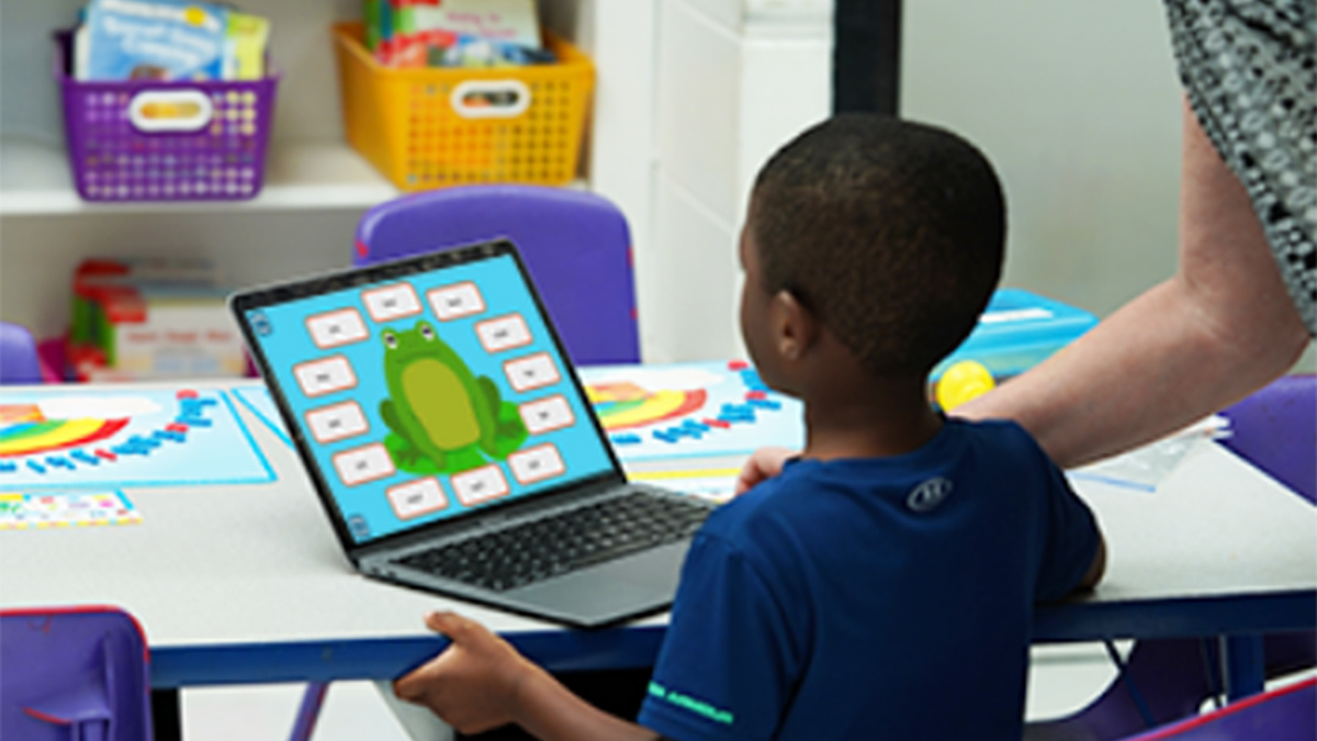 A photo of a boy practicing his phonics skills on a reading program on a laptop computer.