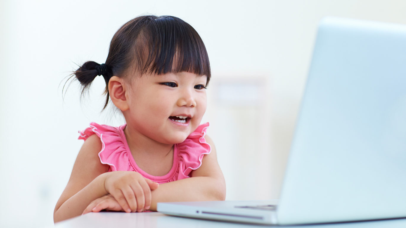 A photo of a girl using a laptop to complete a voice-enabled learning lesson.