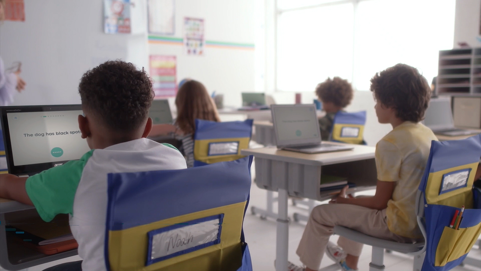 A photo of a classroom of first grade students completing a project on their laptop computers.