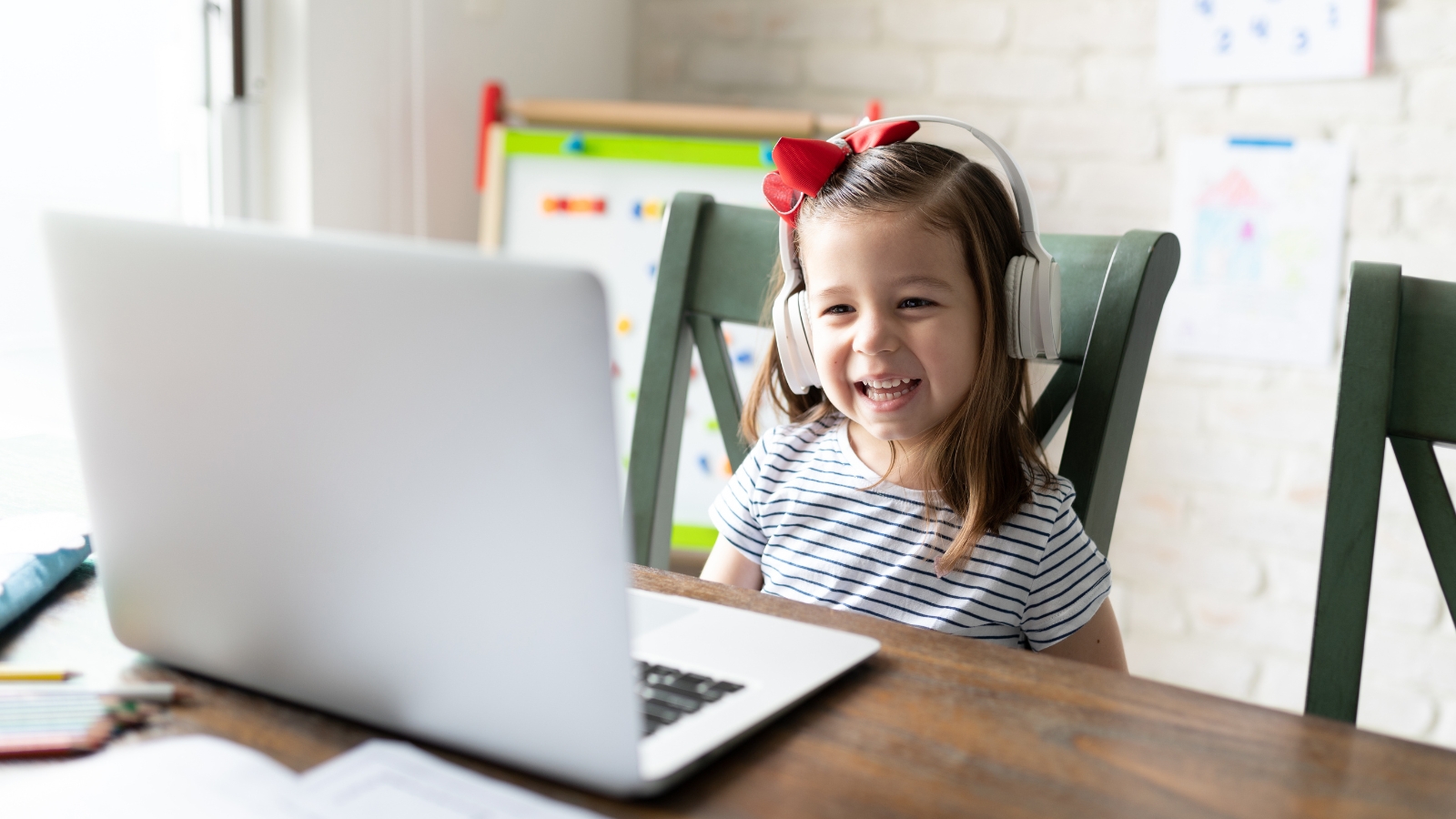 A photo of a girl sitting at a desk, talking into a laptop computer.